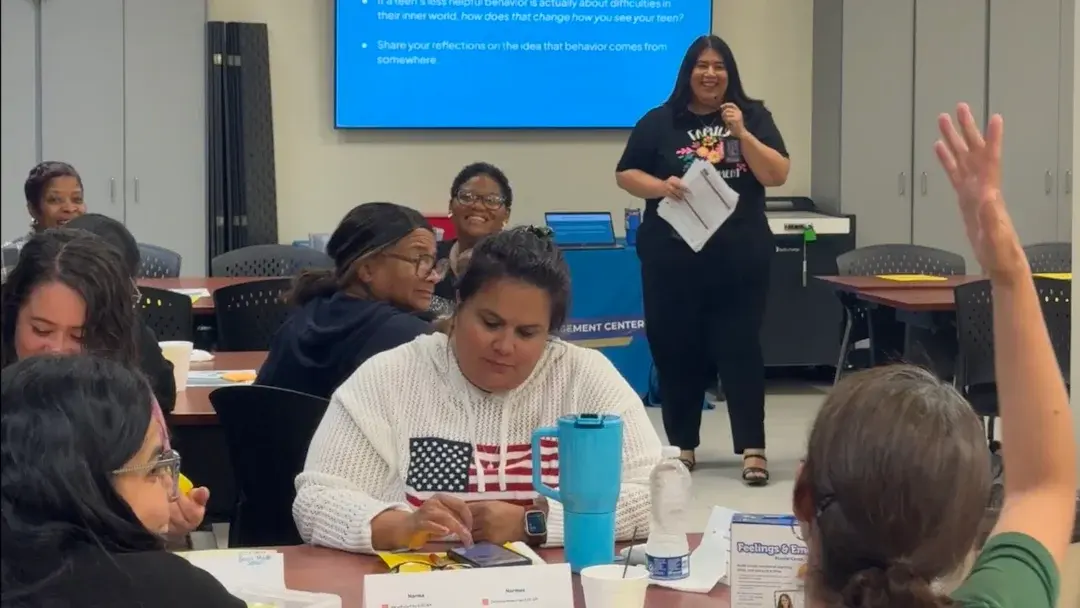 A small group of caregivers in class, one raising a hand